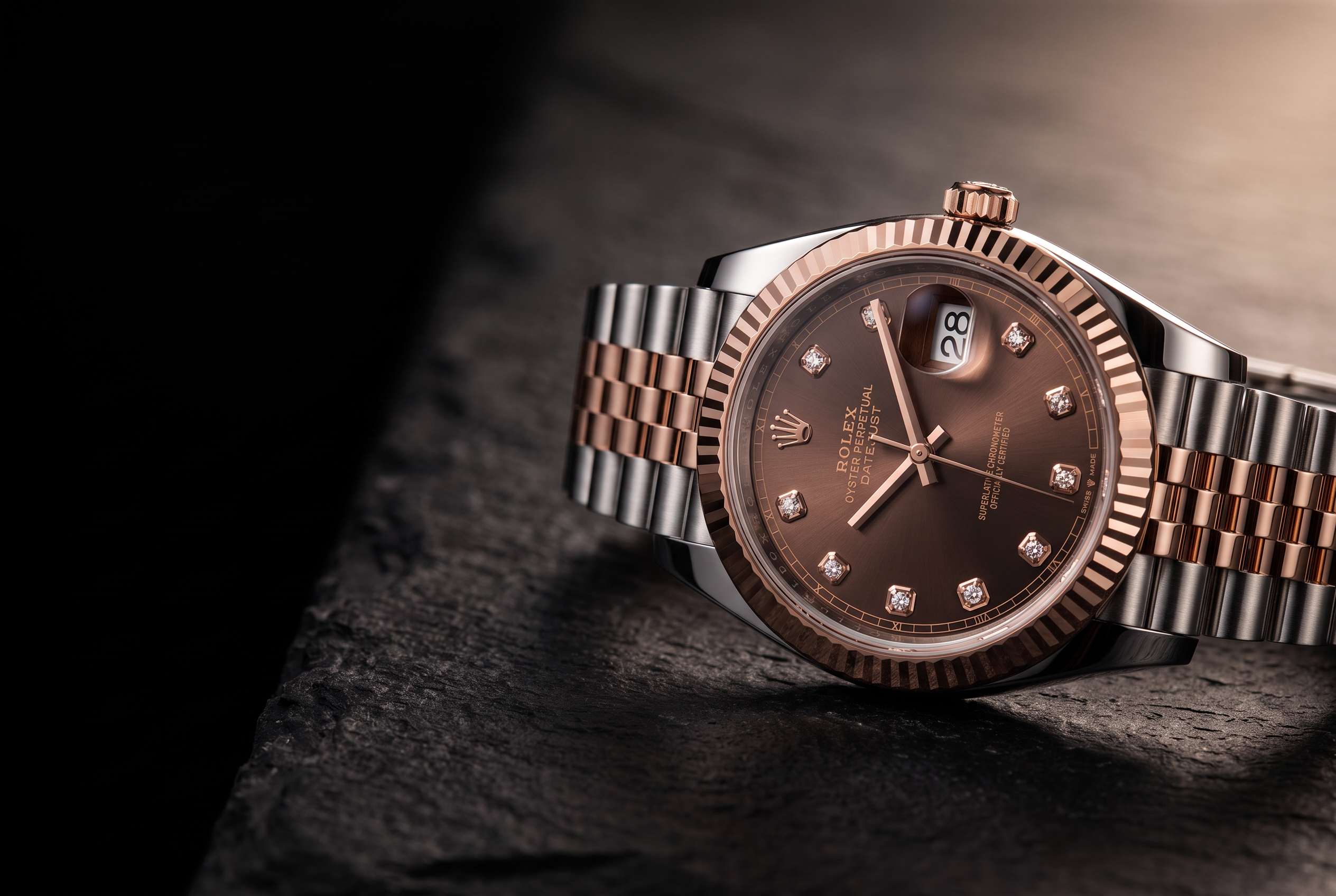 A two-tone steel and rose gold wristwatch with a brown diamond-set dial on dark stone